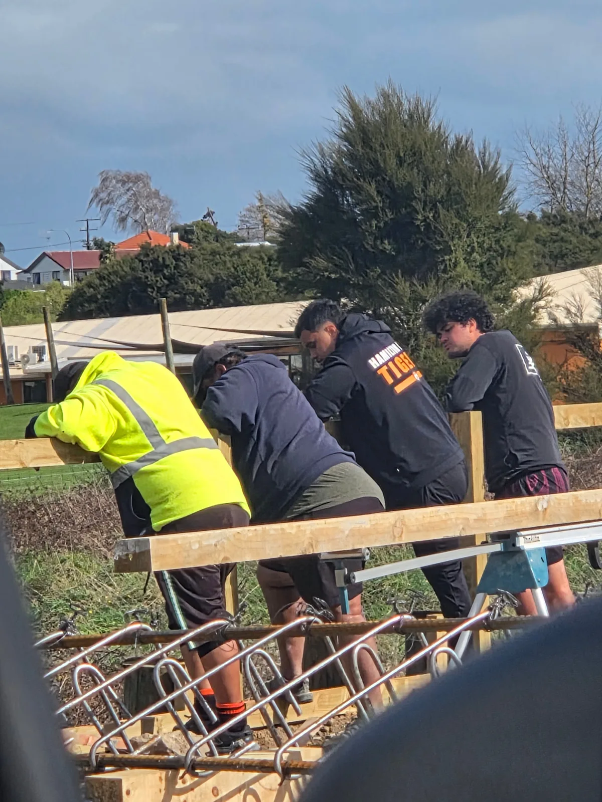 The WAH Greenland team leaning on a fence rail at a building site